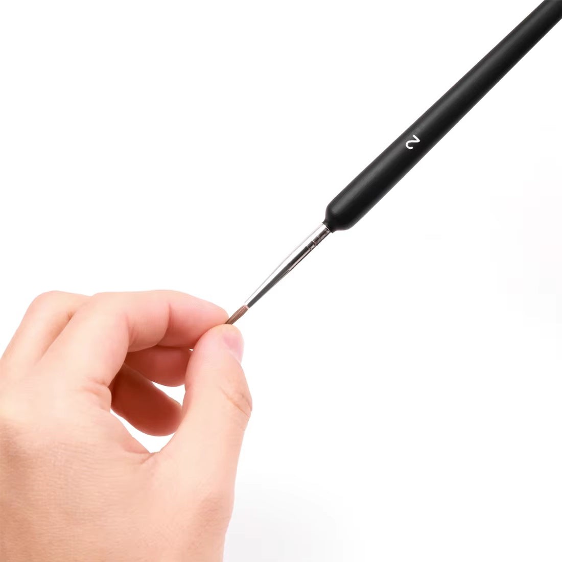 A liner brush held between two fingers, showing its length