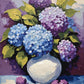 blue and purple hydrangeas in a white ceramic vase with green leaves on a table, paint by numbers kit